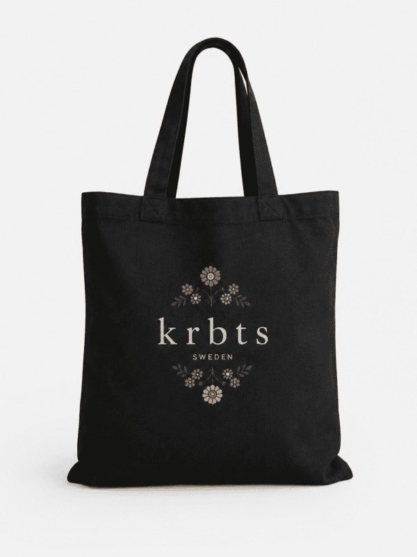 Svart tygväska med blomsterdesign och "krbts" text, perfekt för vardagsbruk.